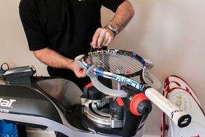 A racket on a stringing machine, in the late stages of the restringing process
